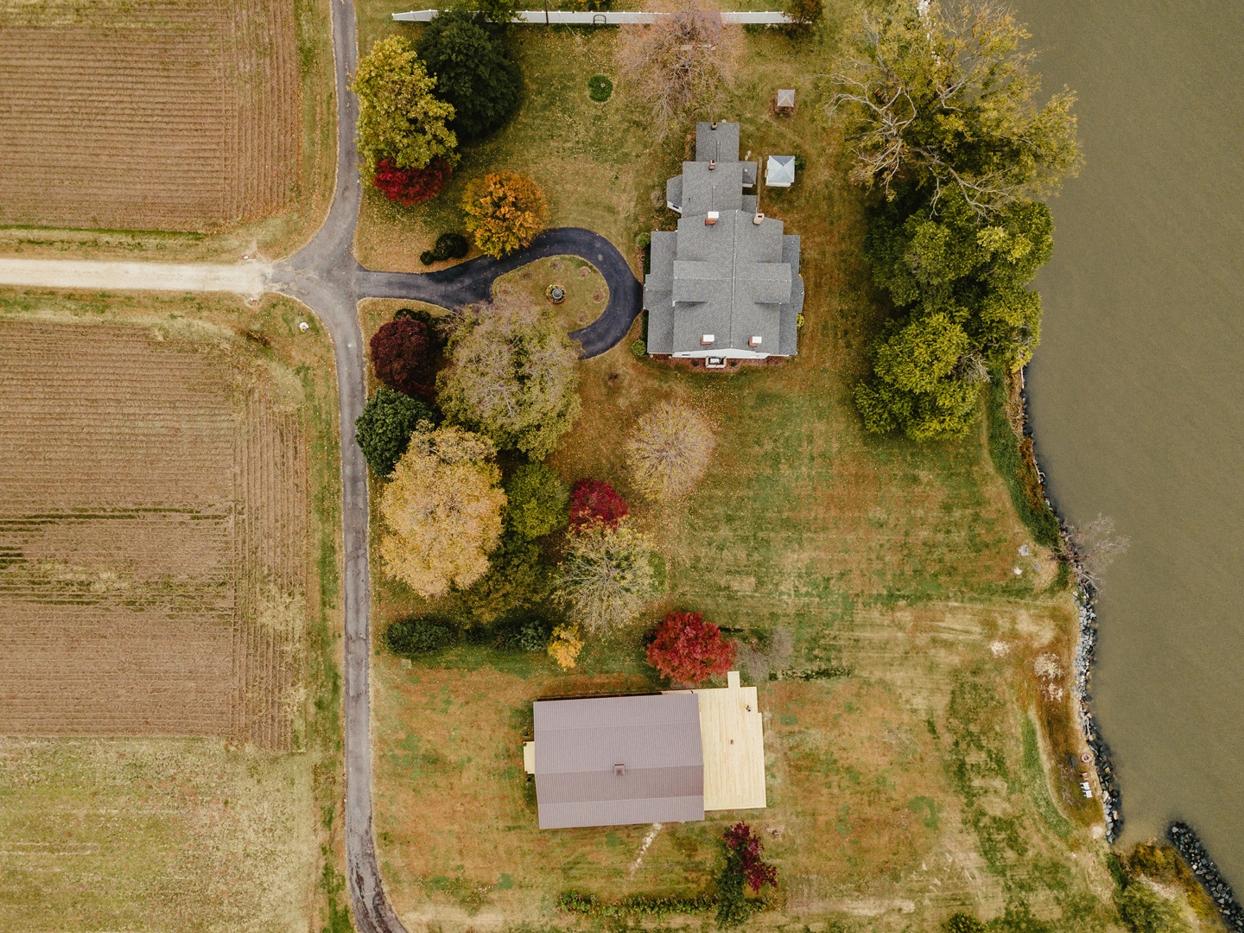 Aerial view of the reception barn at Lower Notley Hall Farm, next to the Wicomico River and surrounded by lush greenery.