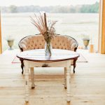 A rustic wooden table and Victorian chair inside the reception barn